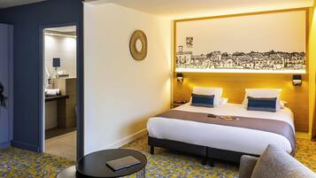 Habitación de hotel con cama, mesita de noche y una pequeña mesa redonda con un control remoto.
