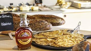 A variety of breads and pastries on display, including a bottle of maple syrup.