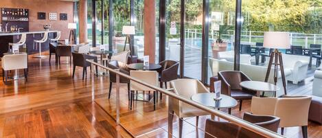 Un espacio interior moderno con bar, asientos y ventanas amplias con vista a una piscina.