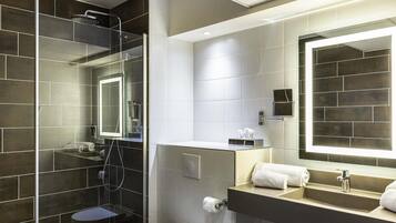 A modern bathroom with a glass-enclosed shower, a toilet, a sink with a mirror, and a towel rack.