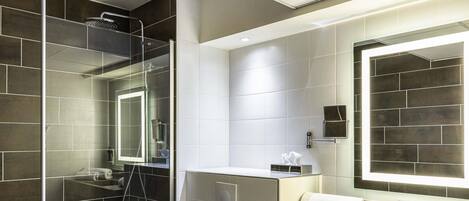 Une salle de bain moderne avec une douche à parois de verre, des toilettes, un lavabo avec un miroir et un porte-serviettes.