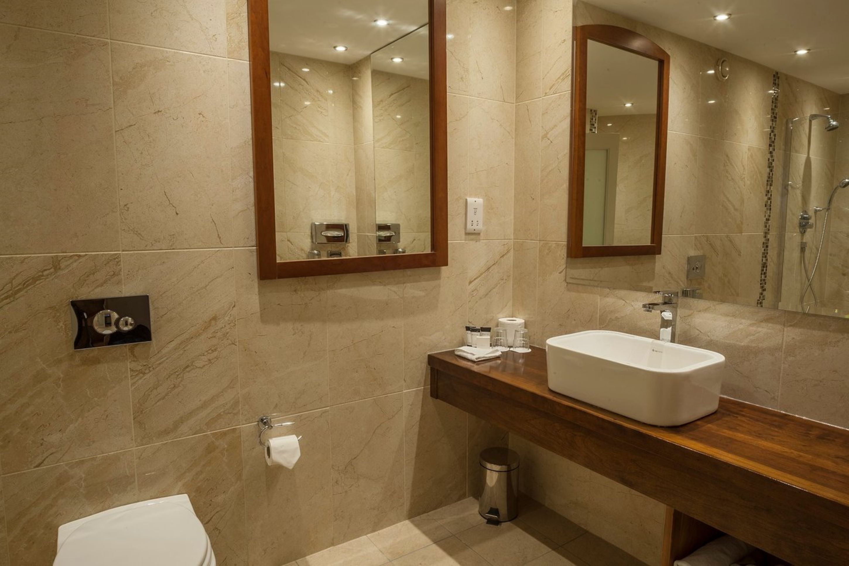 Un baño moderno con un espejo grande, un lavabo blanco y una zona de ducha.