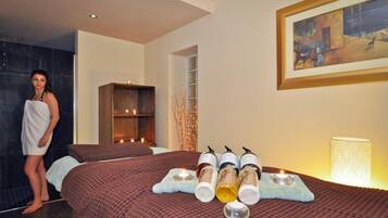 A spa room with a bed, candles, and essential oils.