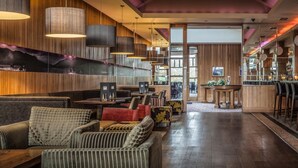 Un interior moderno con paneles de madera, una zona de bar y diferentes disposiciones de asientos.