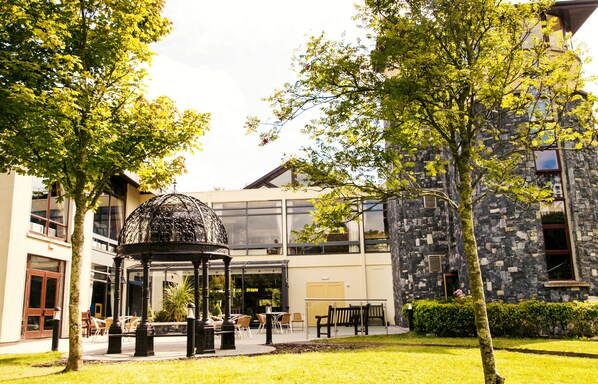 A courtyard with a gazebo, outdoor seating, and a stone building with large windows.