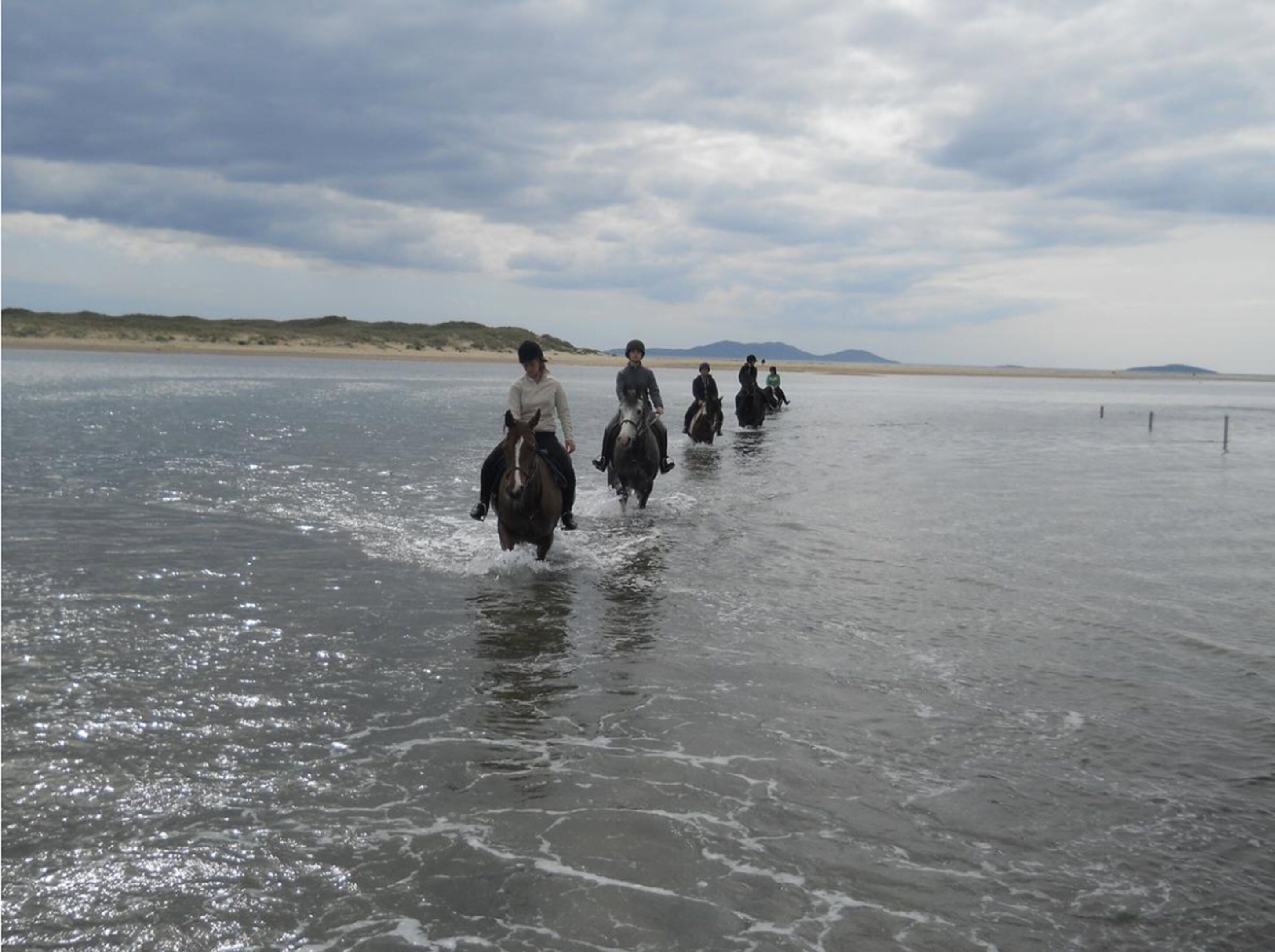 Un grupo de personas montando a caballo sobre una superficie de agua.