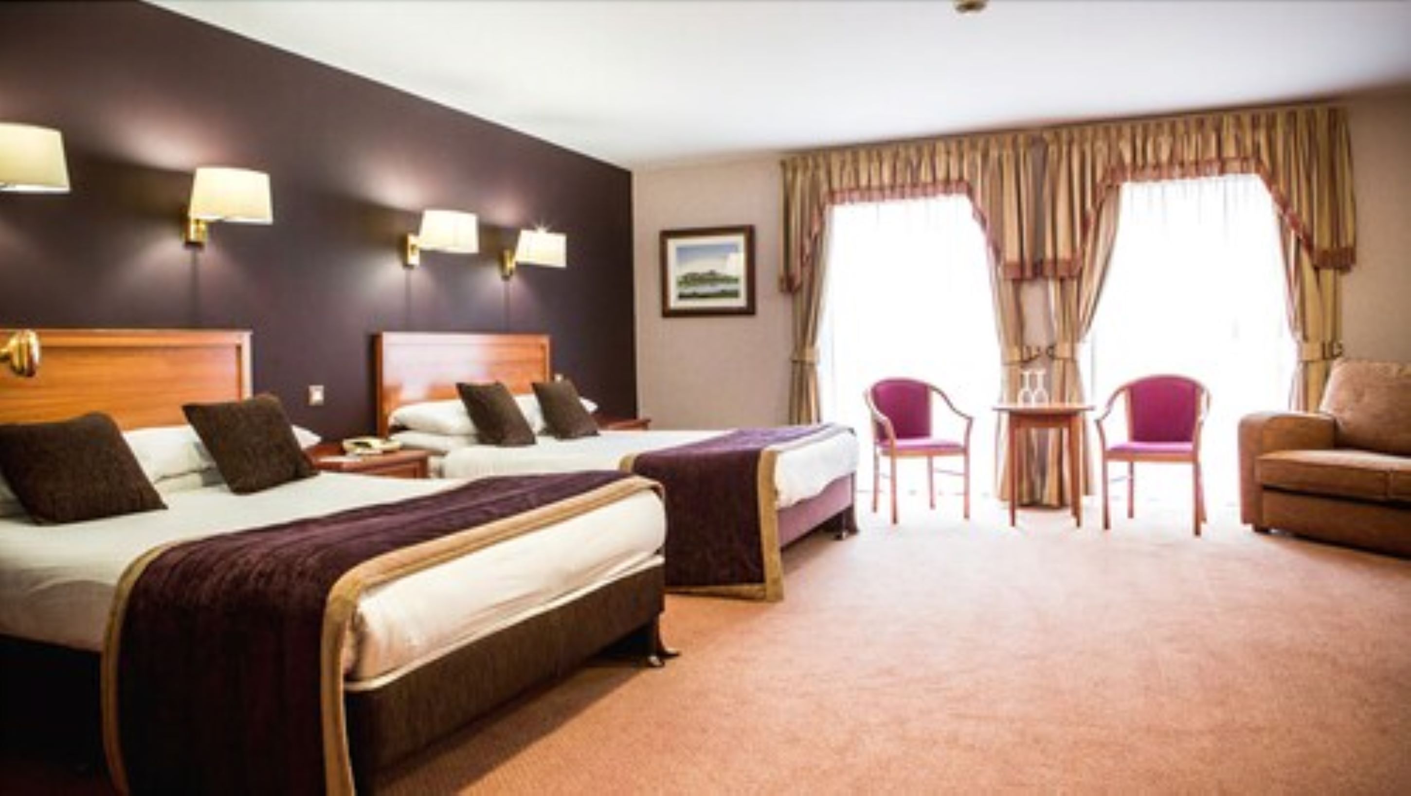 A hotel room with two beds, a sofa, a small table, and a chair.