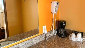 Ein Badezimmer mit einem an der Wand montierten Föhn, einer Kaffeemaschine und einem Korb mit Pflegeprodukten.