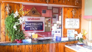 Eine Rezeption im Northgate Inn mit einem 'Welcome'-Schild, einer amerikanischen Flagge und Schildern für den Check-out zu 11:00 Uhr und 14:00 Uhr.
