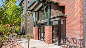 A building entrance with a brick facade, a covered walkway, and a bench. - Clarion Inn & Suites Atlanta Downtown (Atlanta)