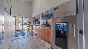 Un moderno vestíbulo de hotel con una recepción, un dispensador de agua y vistas al exterior.