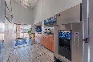 Un moderno vestíbulo de hotel con una recepción, un dispensador de agua y vistas al exterior.