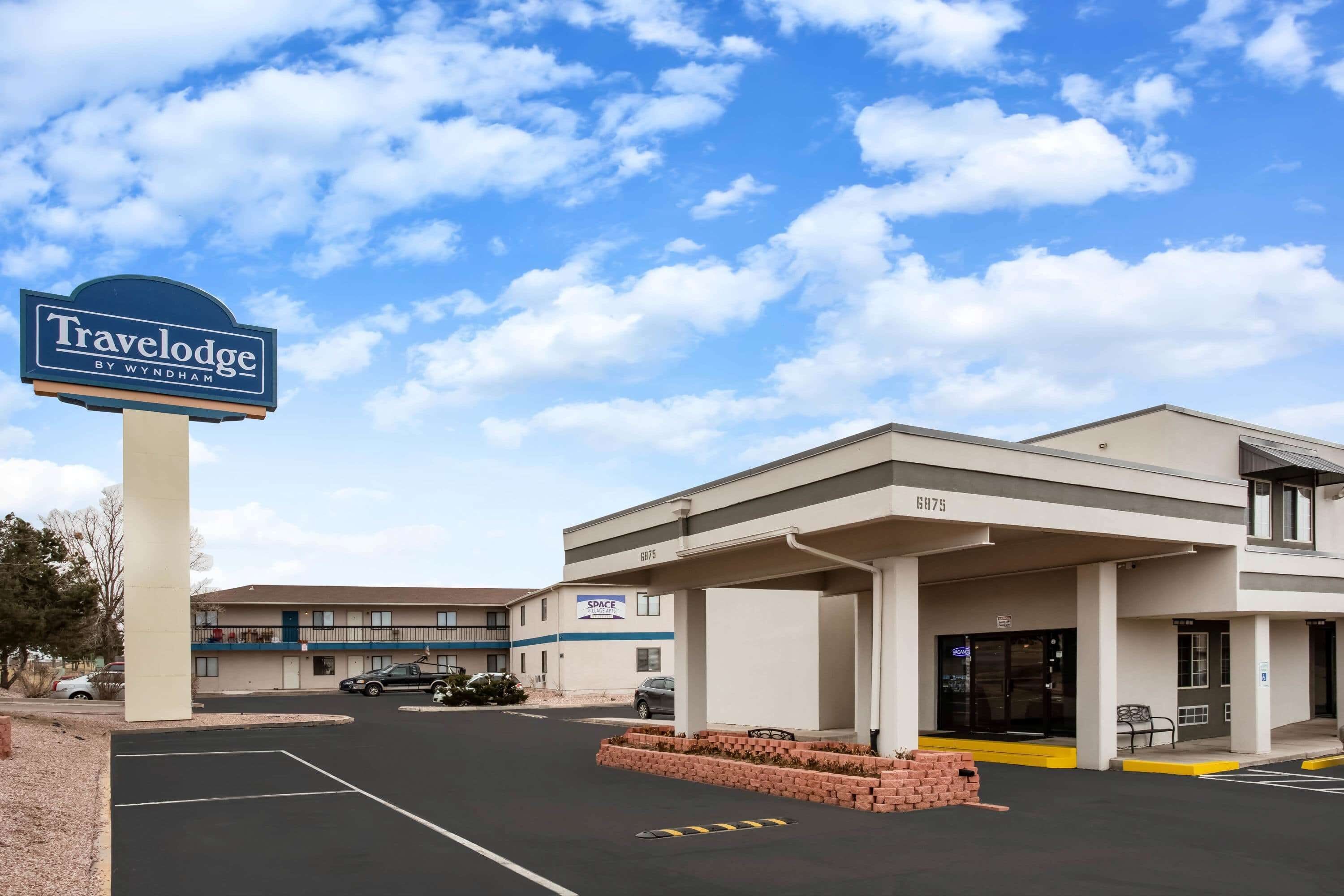 A Travelodge by Wyndham hotel with a parking lot, a covered entrance, and a 'Space' sign on the building.
