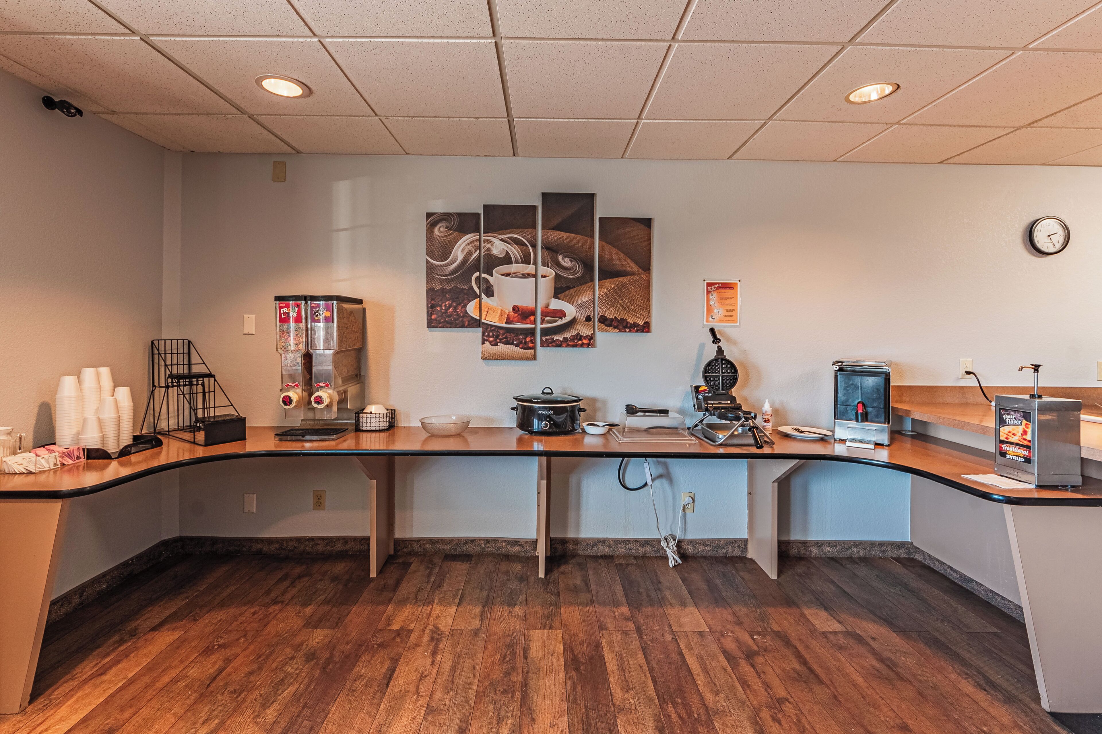 A modern kitchen area with a wooden countertop, a coffee machine, a microwave, and a coffee station with cups and a coffee pot.