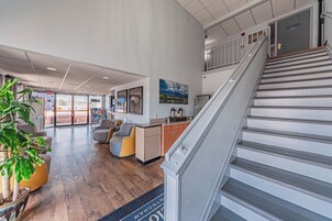 Un vestíbulo amplio con piso de madera, una escalera y vistas al exterior.