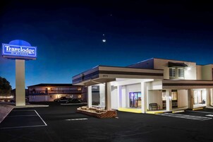 Hotel Travelodge by Wyndham con estacionamiento, un letrero y un edificio de varios pisos con balcón.