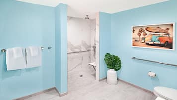 Et badeværelse med lyseblå vægge, en marmorbruser, et hvidt toilet og en plante.