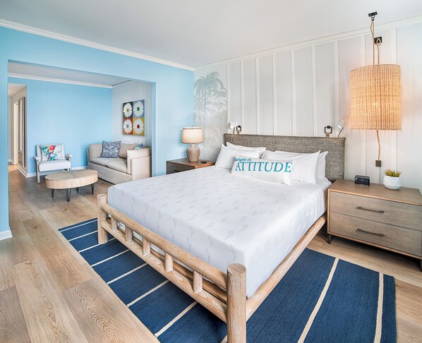 Un dormitorio con una cama grande, una mesita de noche, una lámpara y una silla.