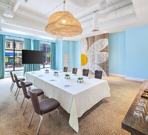 A conference room with a long table, chairs, a large screen, and a decorative wall.