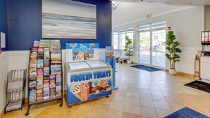 A bookstore with a frozen treats display, a large painting on the wall, and a view of the outside through large windows.