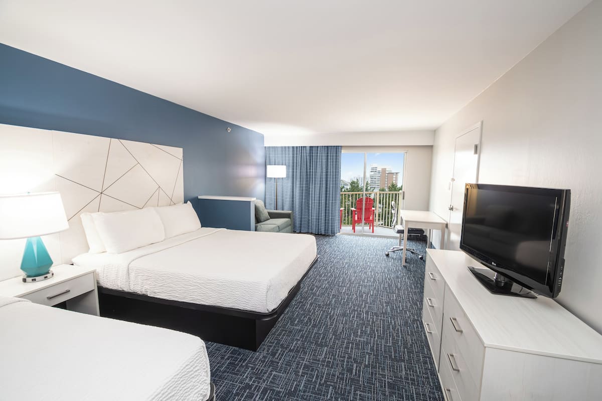 Ein Hotelzimmer mit einem großen Bett, einem Fernseher, einem Schreibtisch und einem Sessel.
