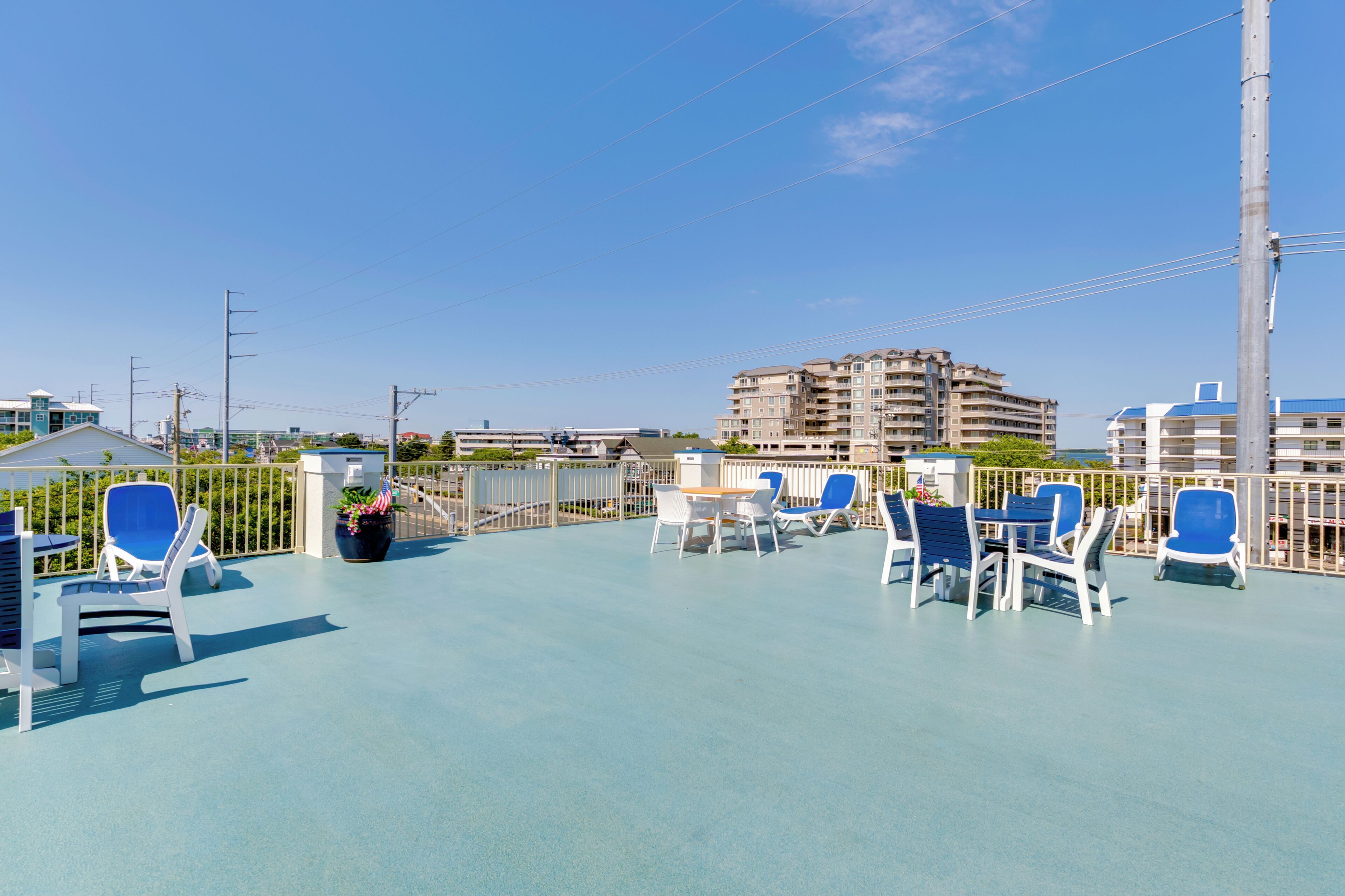 A rooftop terrace with outdoor seating and a view of a multi-story building.