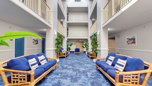 Een hotel lobby met een centrale zithoek, een trap en uitzicht op de bovenverdiepingen.
