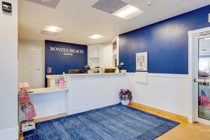 A reception area with a blue wall, a reception desk, a white counter, a blue carpet, and a potted plant.