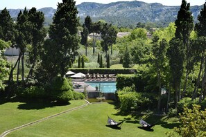 A lush garden with a pool, surrounded by tall trees and a mountain backdrop. - Hôtel de l'Image (St.-Rémy-de-Provence)