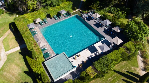 Alberca techada, alberca al aire libre y sombrillas en la alberca