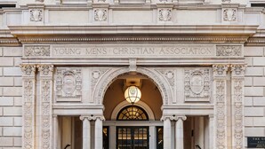The entrance to the Young Men's Christian Association building with a grand arched doorway, columns, and a staircase leading up to the entrance. - The Guild Hotel, San Diego Downtown, a Marriott Tribute Portfolio Hotel (San Diego)