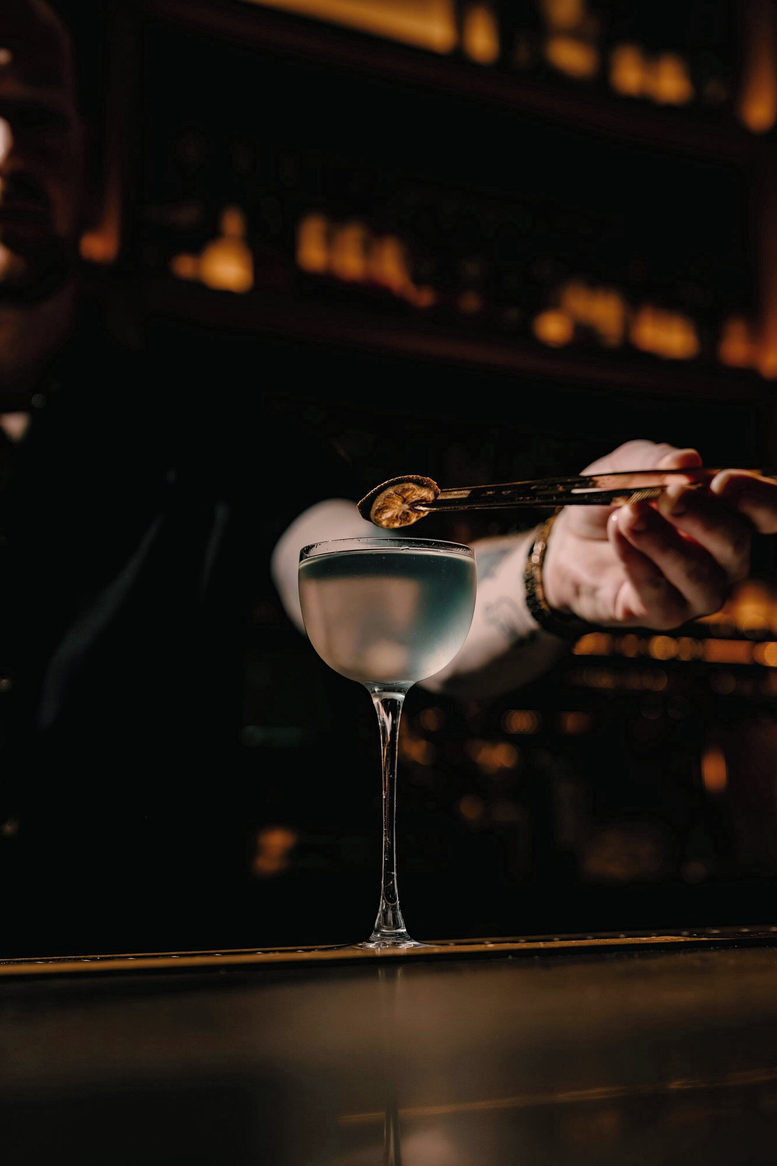 A bartender pouring a drink into a martini glass.