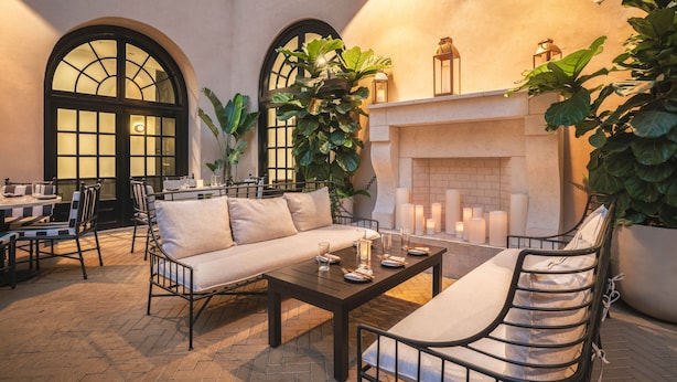 A cozy outdoor seating area with a fireplace, cushioned seating, and potted plants. - The Guild Hotel, San Diego Downtown, a Marriott Tribute Portfolio Hotel (San Diego)