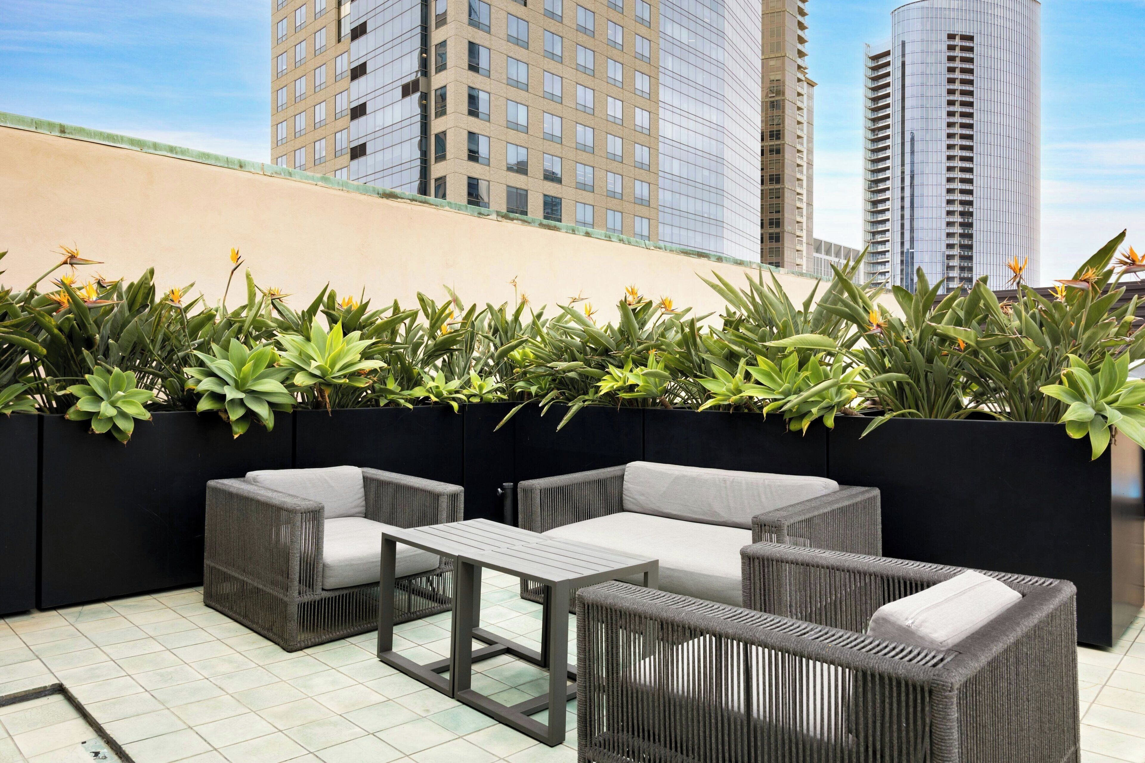 An outdoor seating area with wicker furniture and a low wall of greenery.