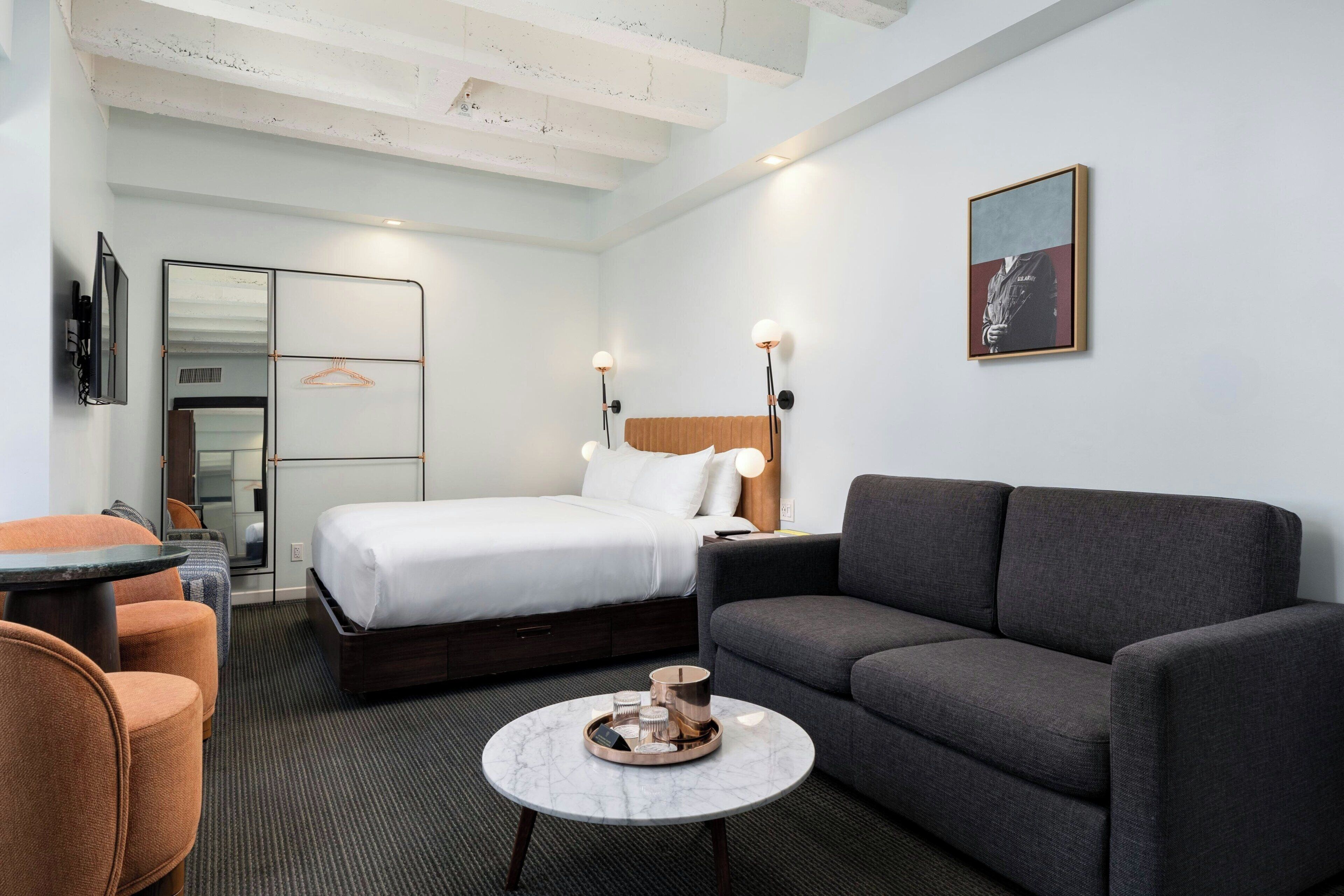 Ein modernes Hotelzimmer mit Bett, Sofa und einem kleinen runden Tisch mit Tablett.