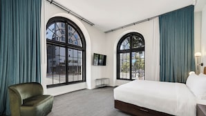 A hotel room with a large bed, a chair, a TV, and two large windows with curtains. - The Guild Hotel, San Diego Downtown, a Marriott Tribute Portfolio Hotel (San Diego)