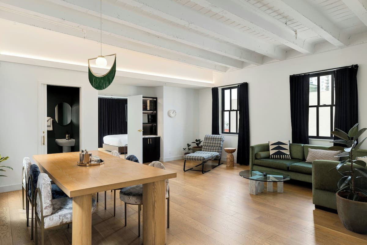 Un amplio salón con una mesa de comedor de madera, un sofá verde y un sillón mecedora.