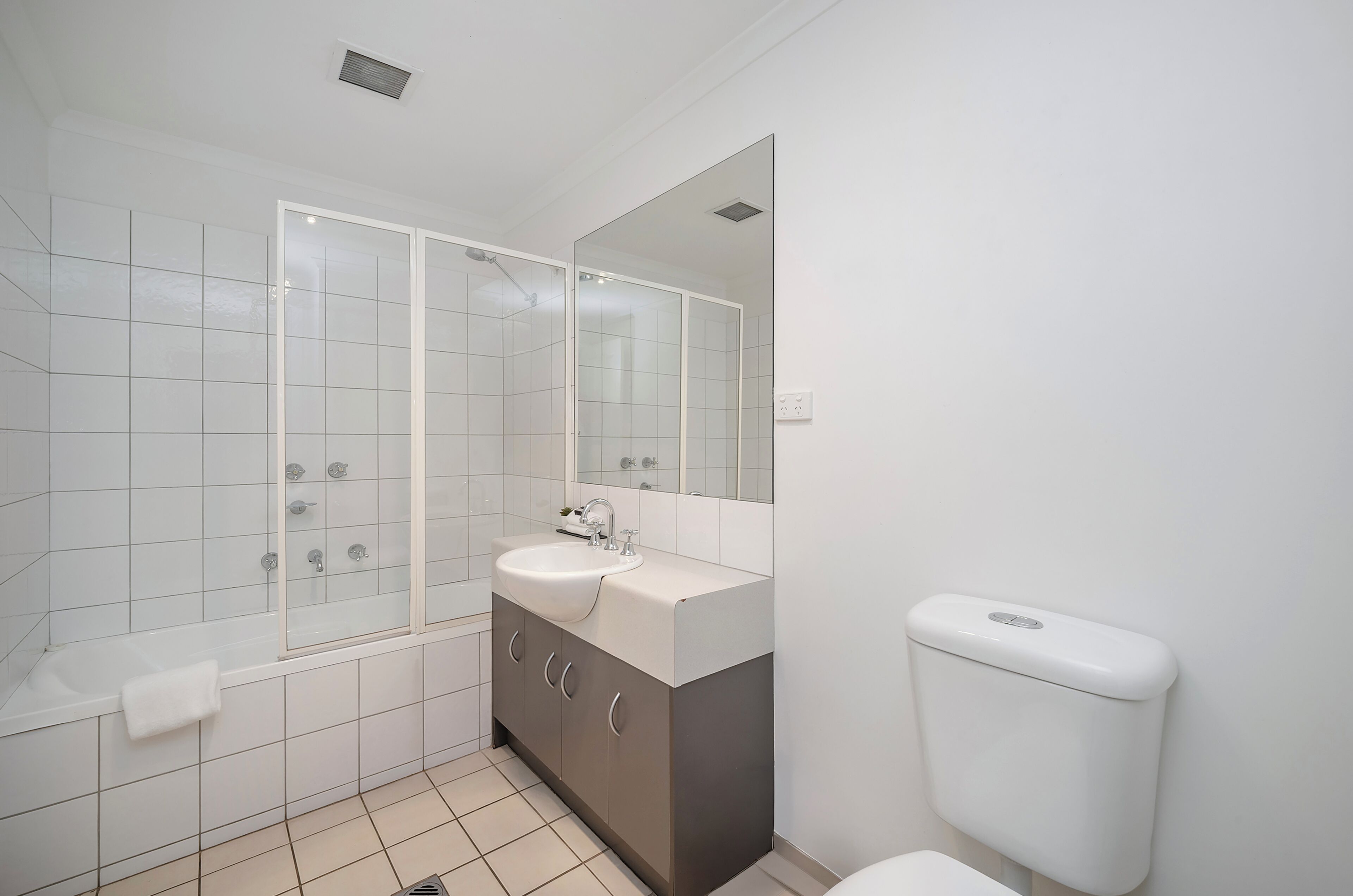 Un baño moderno con bañera, lavabo, inodoro y un espejo grande.