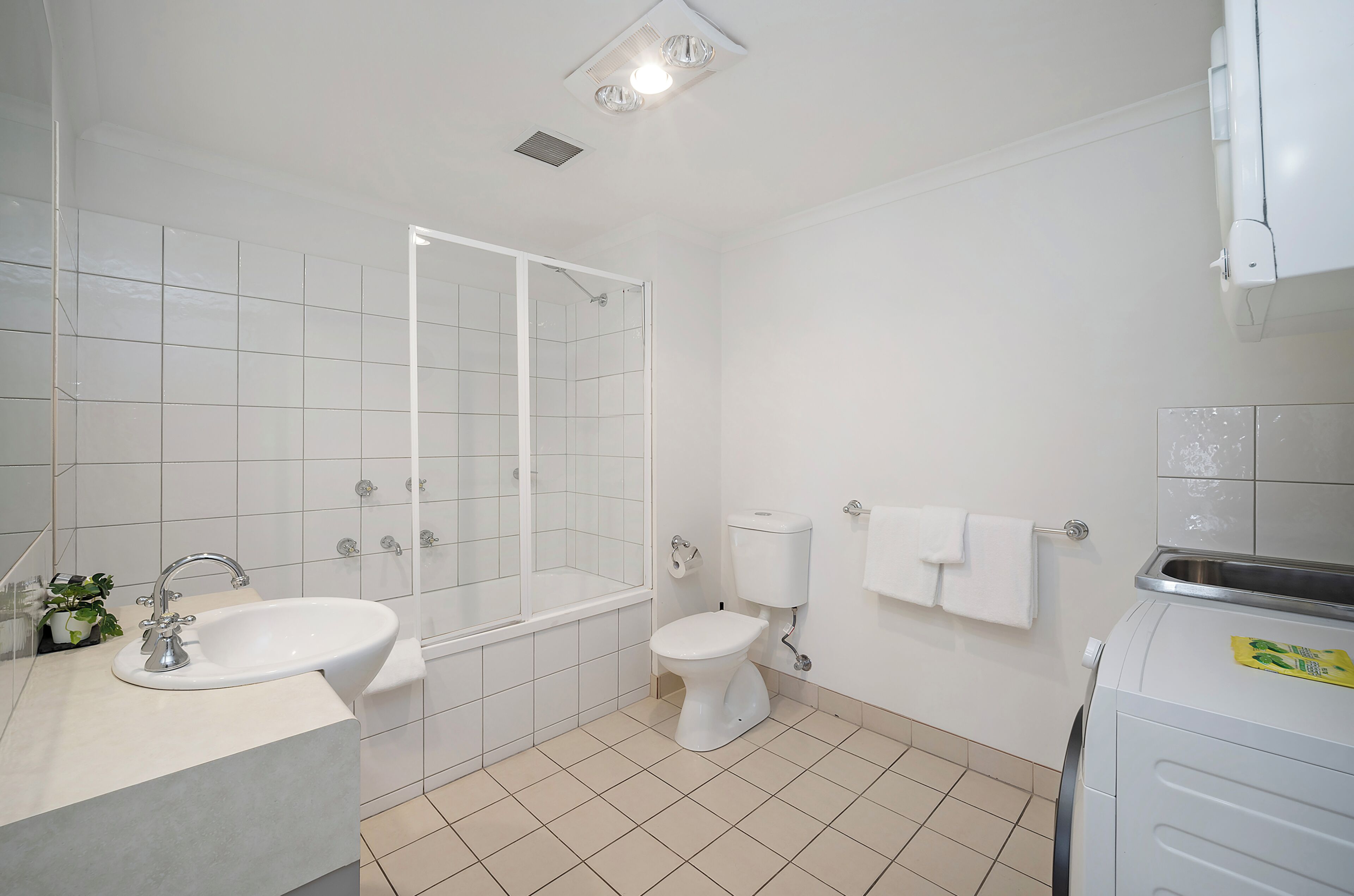 Un baño con lavamanos, inodoro, bañera y lavadora.