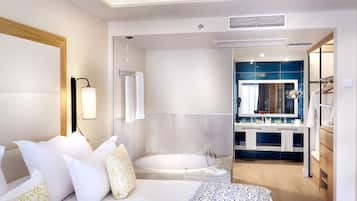 A modern hotel room with a large bed, a separate bathroom with a bathtub, and a walk-in closet.