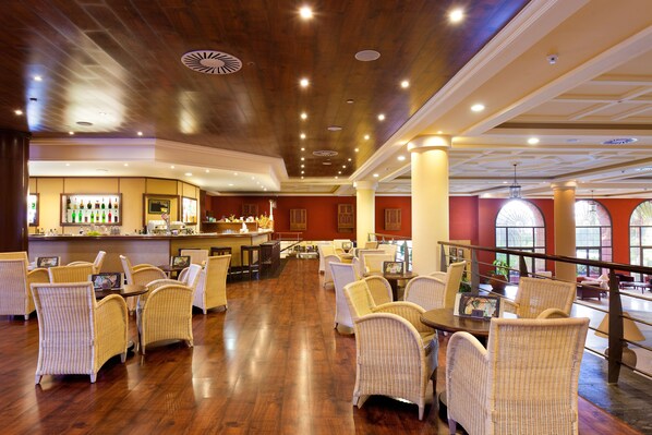 A spacious lobby with wicker furniture, a bar area, and large windows.