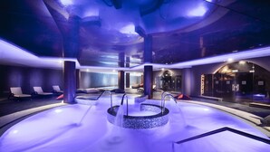 A spa area with a central hot tub, lounge chairs, and a reception desk. - Gran Tacande Wellness & Relax Costa Adeje (Adeje)