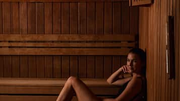 A wooden sauna with benches, a slanted ceiling, and a wooden wall.