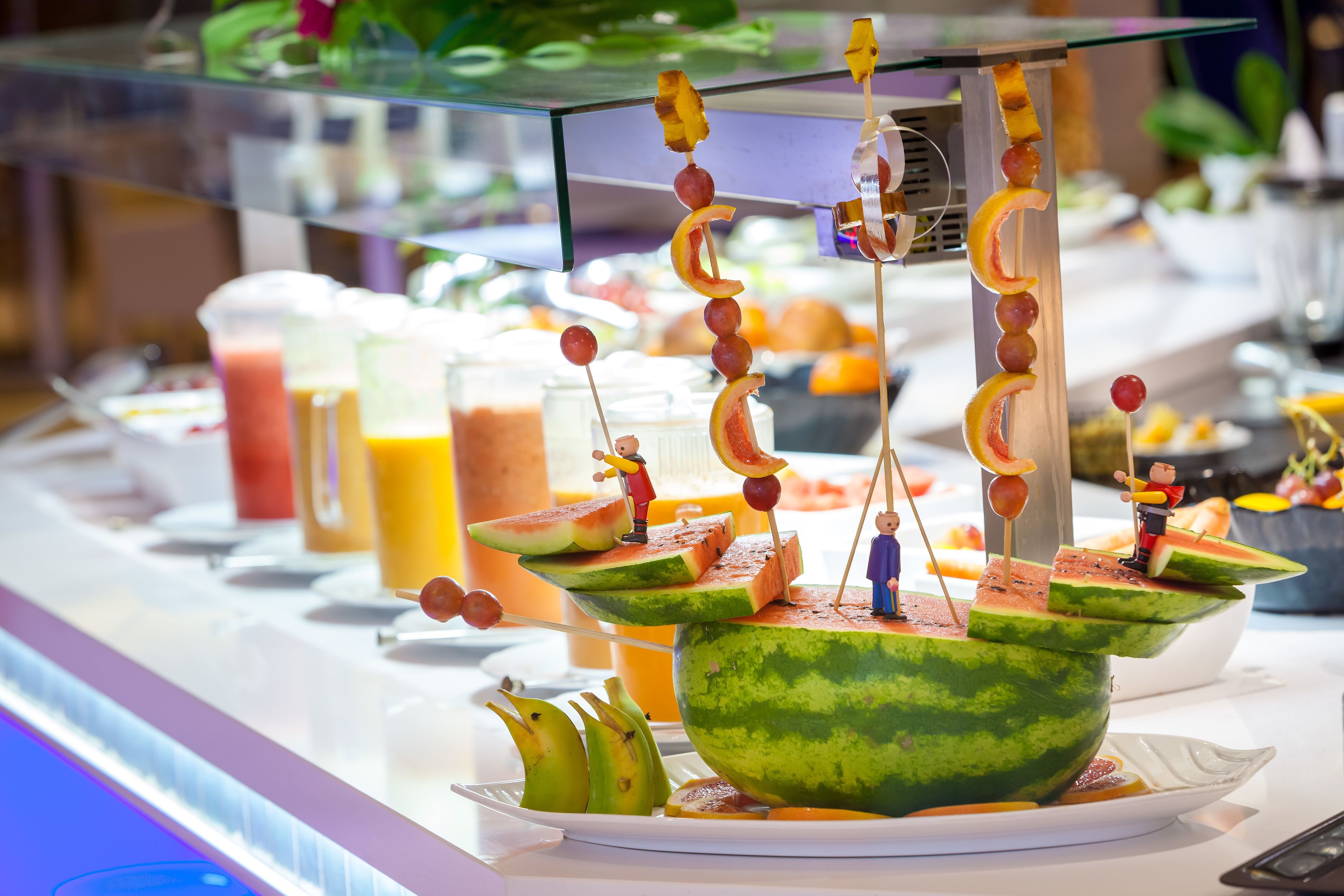 Un bufé con una llamativa composición central de sandía, que incluye figuras en miniatura y brochetas de fruta.