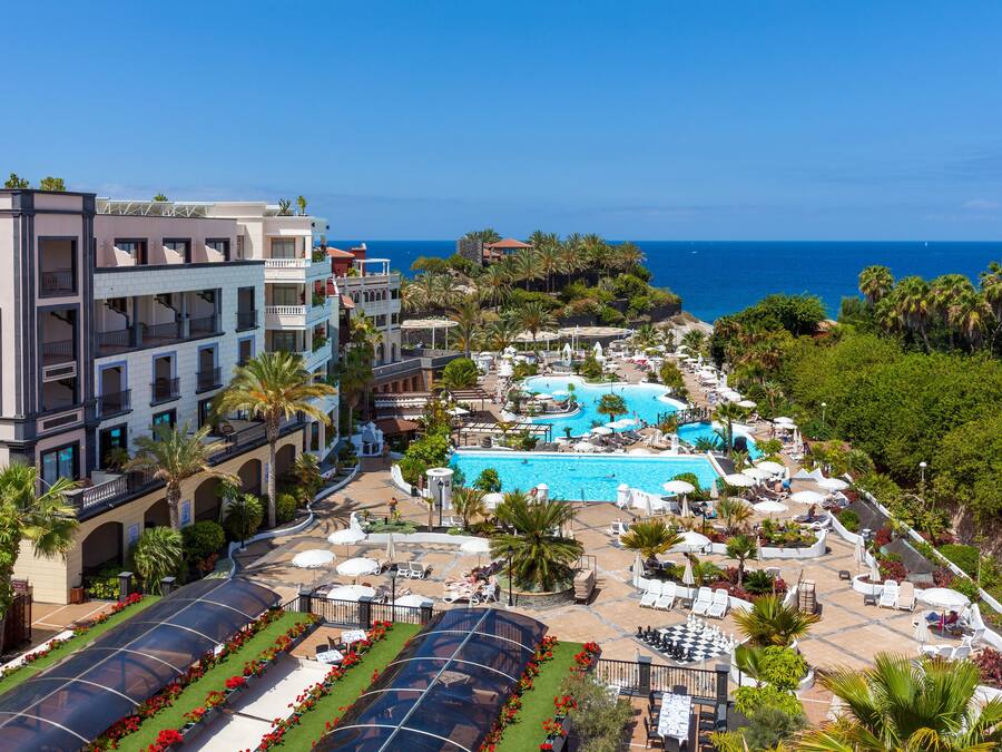 Un resort con varias piscinas, zonas de estar al aire libre y vistas al océano.