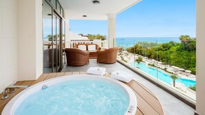 A balcony with a hot tub, wicker chairs, and a view of a pool and ocean. - Gran Tacande Wellness & Relax Costa Adeje (Adeje)