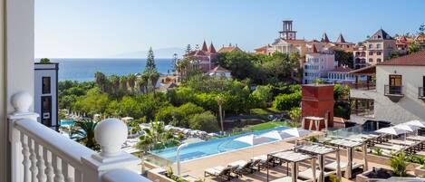 A resort with a pool area, lounge chairs, and a view of the sea.