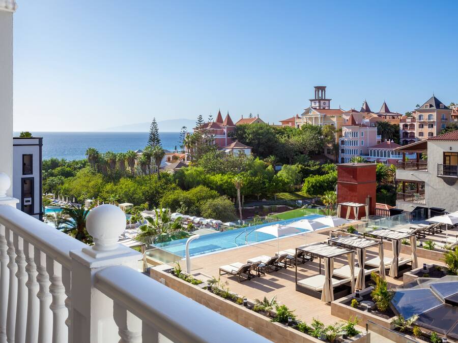 Un resort con piscina, sillones de descanso y vistas al mar.