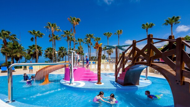 Un espace piscine comprenant un toboggan et une structure de jeux aquatiques.