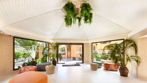 Un hall d’entrée spacieux au design moderne, comprenant un grand espace salon, des plantes en pot et une vue sur l’espace extérieur.